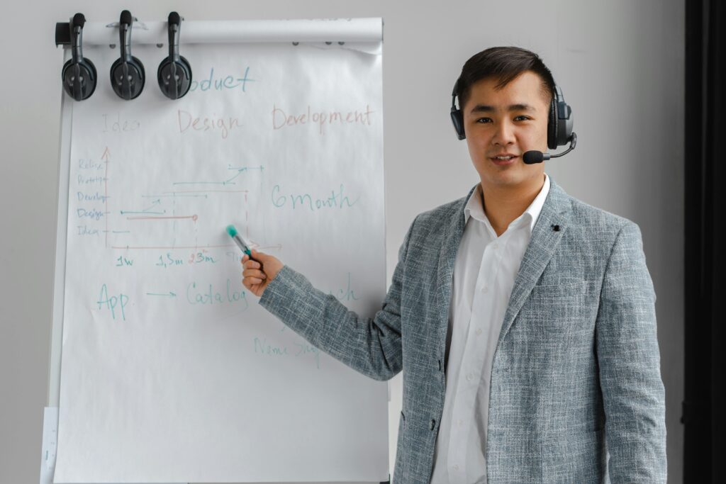 A professional in a suit with a headset presenting on a flip chart.